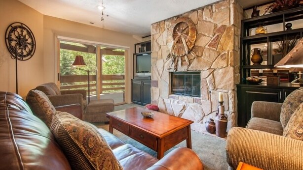 A living room with a stone fireplace, leather sofas, and a television. - Platinum Rated 2BR Sleeps 7/8 - Walk to the Slopes, Downtown Location,Location!! (Park City)