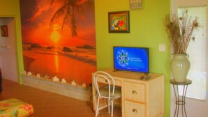 Una habitació amb un mural gran de ponent, un escriptori amb un ordinador, una cadira i un vas amb plantes seques.