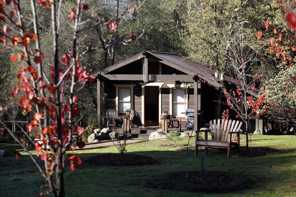 Une cabane dotée d’une véranda, d’un coin repas et d’un grand fauteuil.