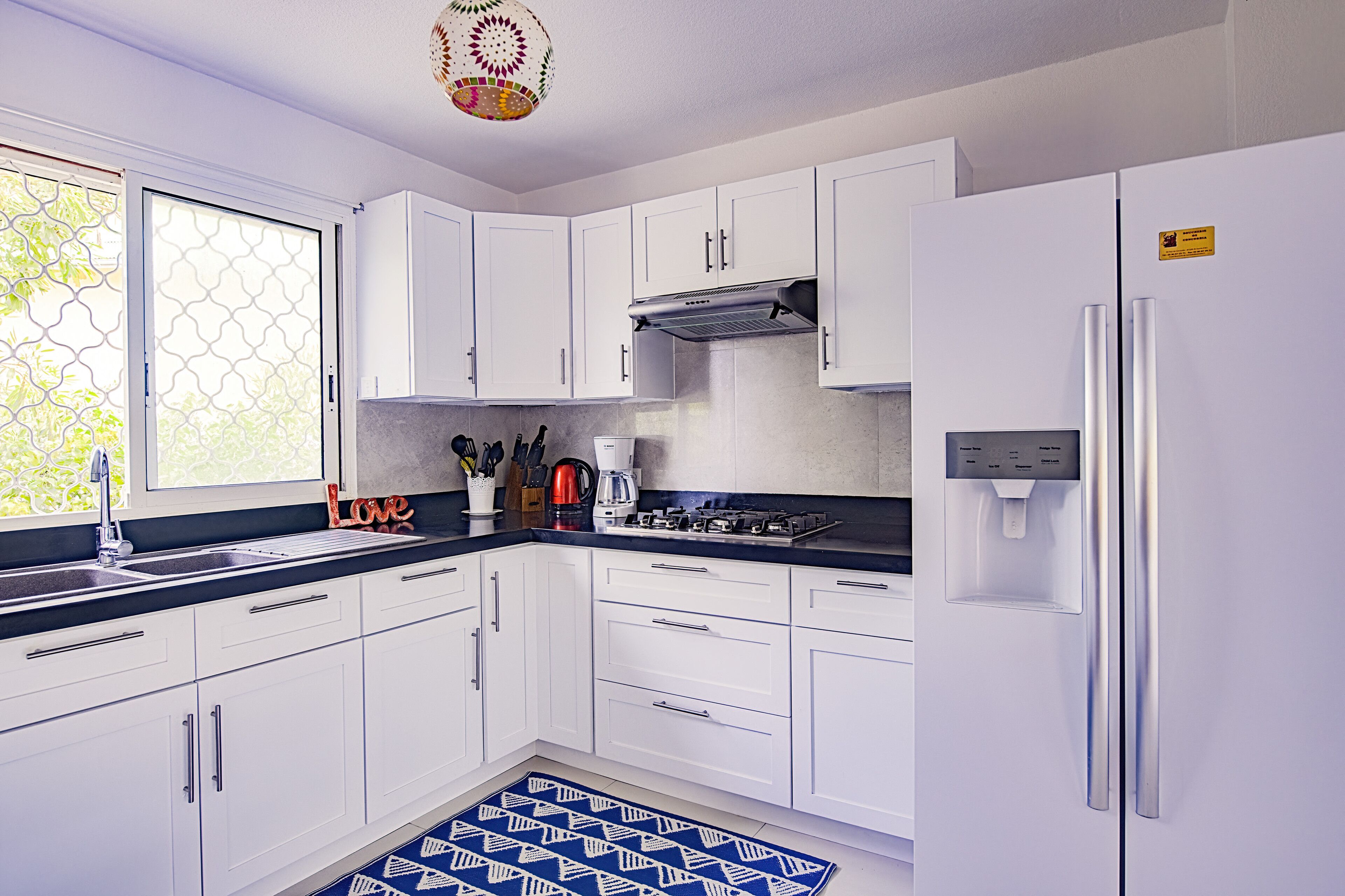 A modern kitchen with white cabinets, a gas stove, and a built-in refrigerator.