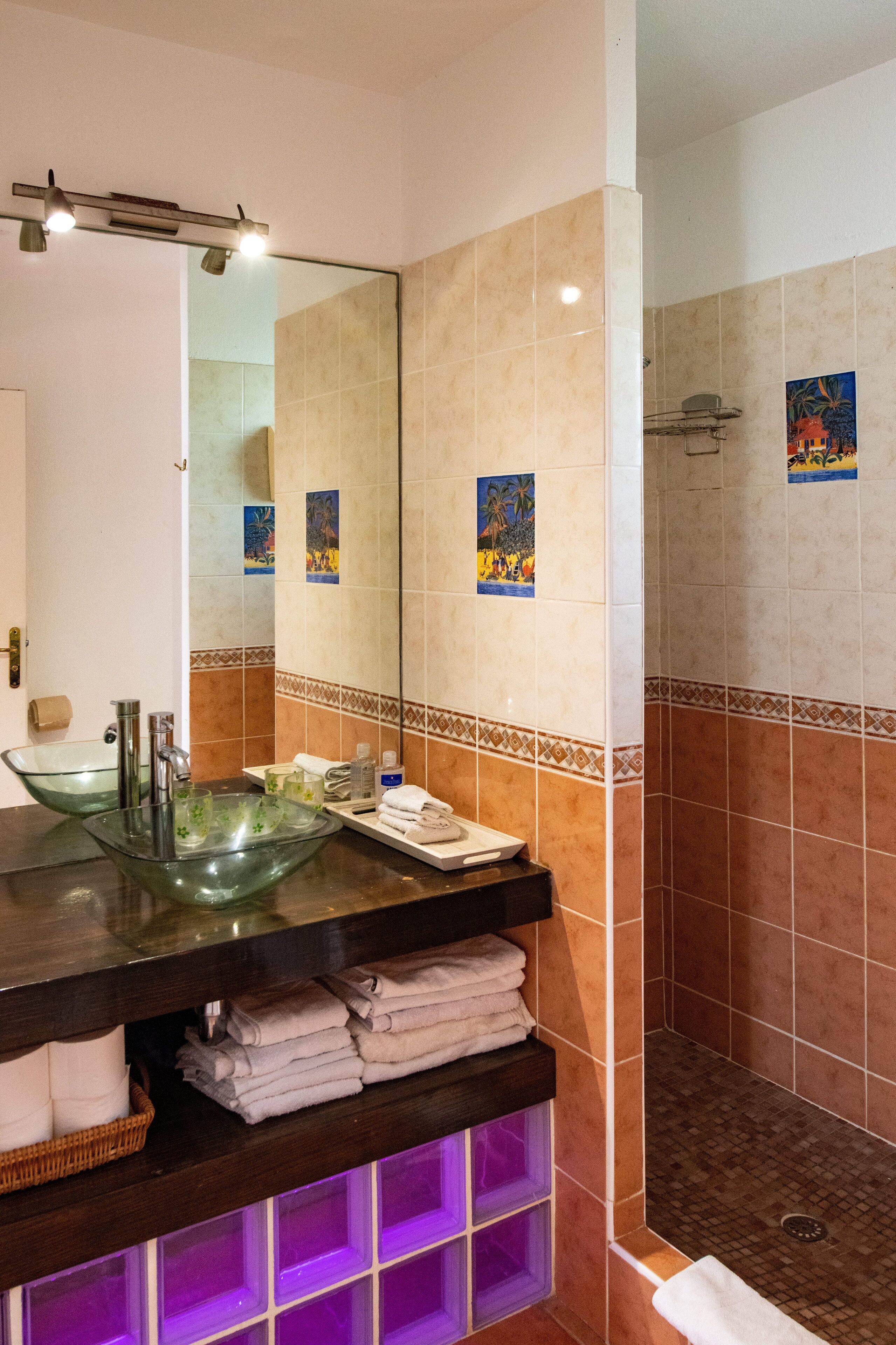 A bathroom with a glass sink, a large mirror, and a shower area.