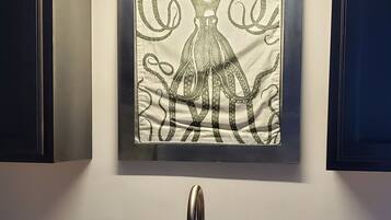 A kitchen with a granite countertop, a stainless steel sink, and a framed artwork above the sink.