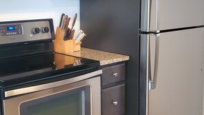 A kitchen with dark cabinets, a stainless steel refrigerator, a built-in oven, and a wooden utensil holder. - August 22-29 Available Due to Cancellation!!! Accepting bookings for Summer 2027 (Beach Haven)