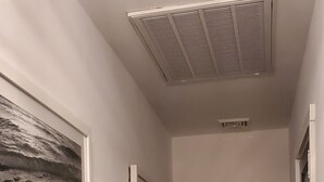 A hallway with a ceiling vent, a framed picture on the left, and a chair in the distance. - August 22-29 Available Due to Cancellation!!! Accepting bookings for Summer 2027 (Beach Haven)