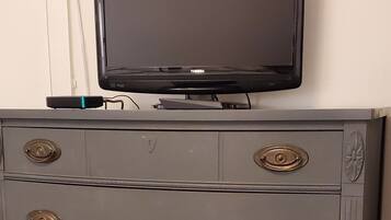 A grey dresser with multiple drawers and a flat-screen TV on top.