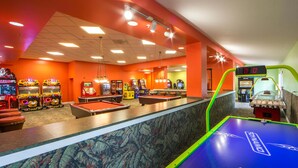 Un espace dédié aux tables de billard, équipé d’un tableau de score numérique, de tables de billard et de divers jeux d’arcade.