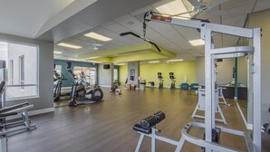 Une salle de sport spacieuse, dotée de divers appareils d’exercice, de grandes fenêtres et d’un intérieur lumineux.