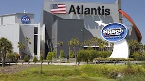 Un grand bâtiment portant le nom «Atlantis» et arborant le logo de la NASA, ce qui indique qu’il s’agit d’un établissement lié à l’exploration spatiale.