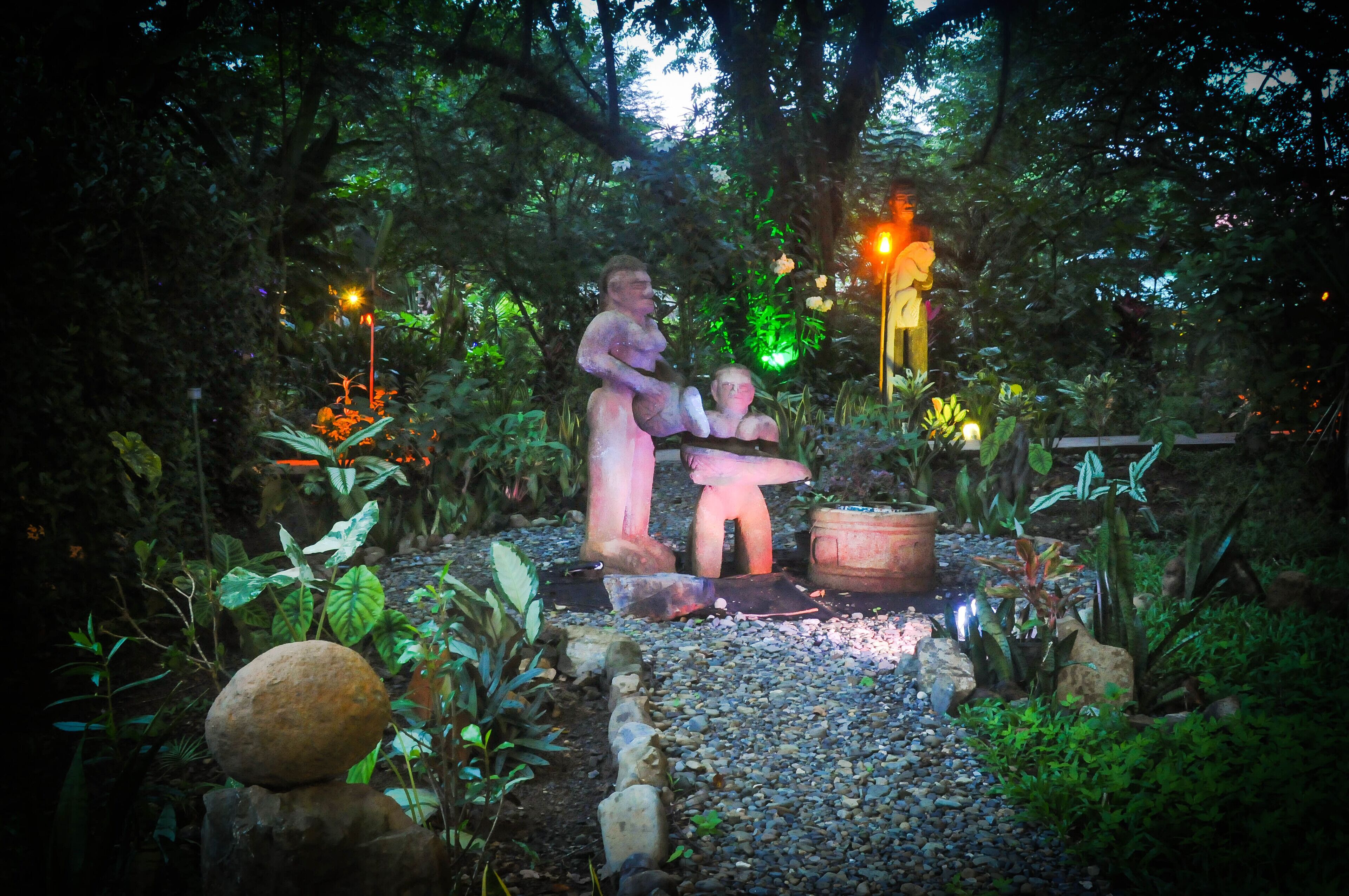 A garden with statues, a stone ball, and a pathway.