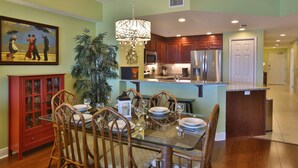 A dining area with a glass table, wooden chairs, and a red cabinet.