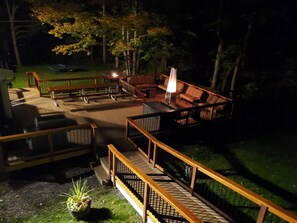 An outdoor deck with wooden railings, a fire pit, and seating areas.