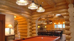 Un tavolo da biliardo in una baita di legno con pareti in legno e lampadari.