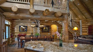 Interno di una baita in legno con zona pranzo, cucina e un balcone.
