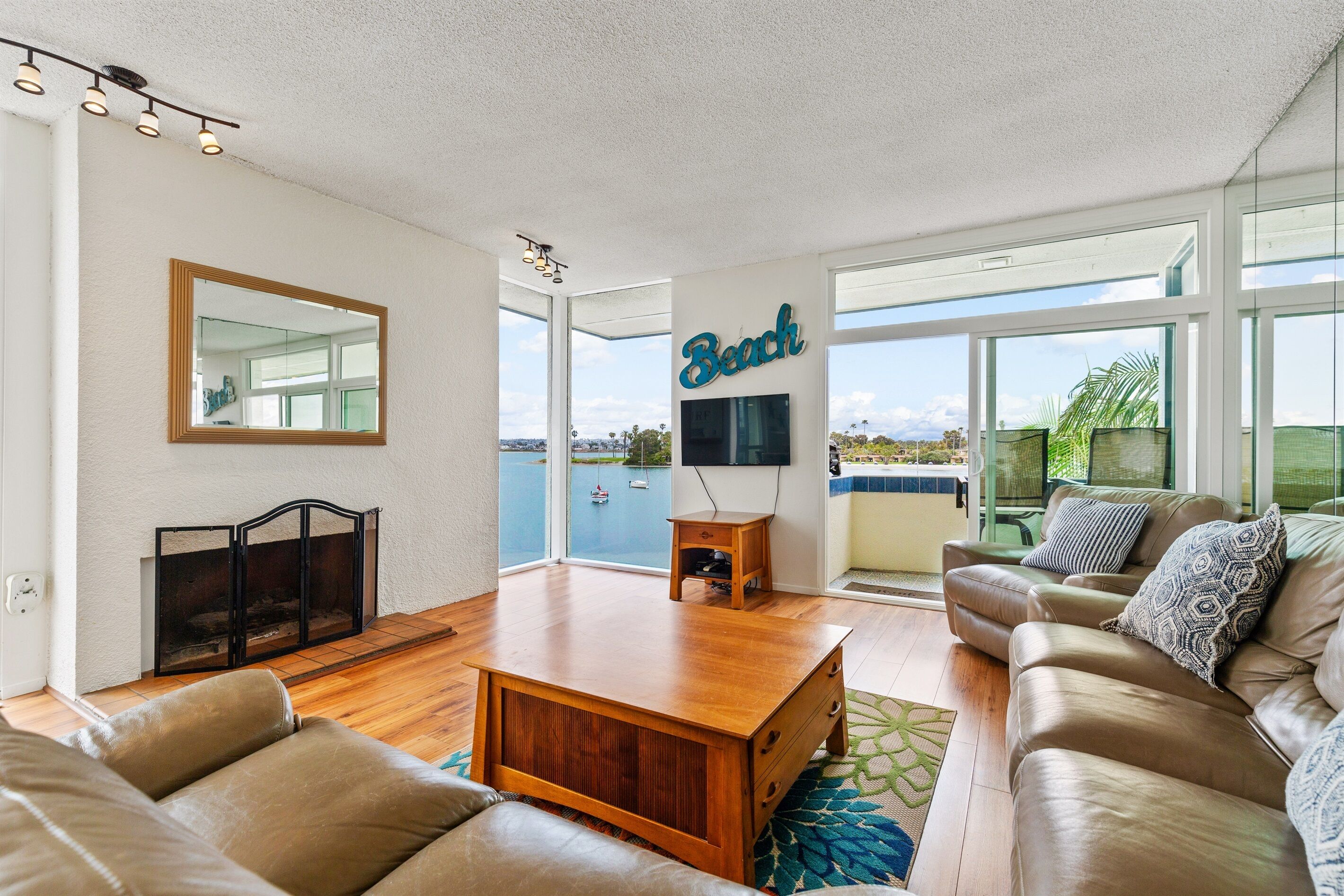 A spacious living room with a large window, a fireplace, a sofa, and a television.