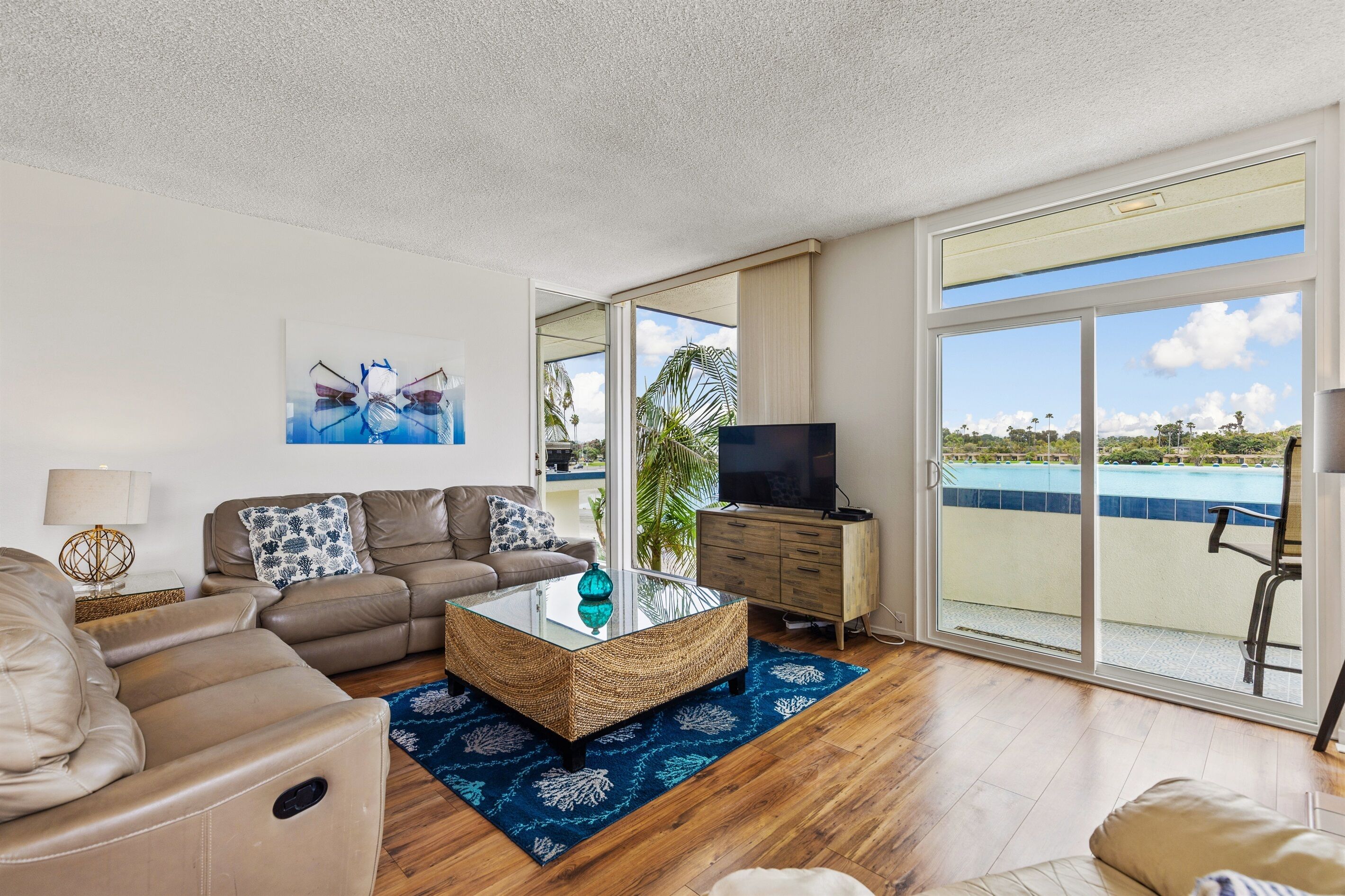 A modern living room with a sofa, a glass coffee table, and a TV.