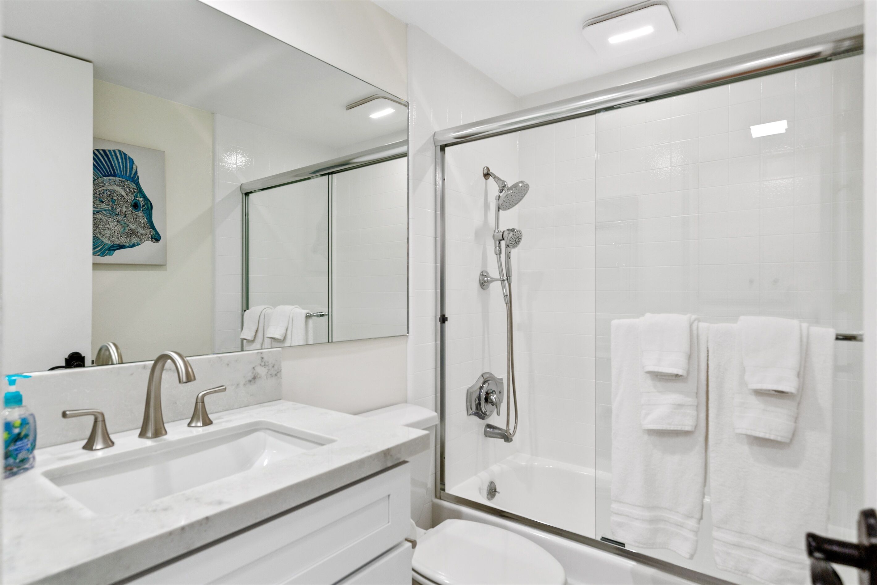 Une salle de bain moderne dotée d’une douche à parois de verre, d’un meuble-lavabo à deux vasques et d’un grand miroir.
