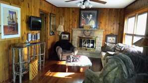 A cozy room with wooden walls, a fireplace, a television, and a couch. - Lakeside cabin retreat; perfect getaway for winter sports, four seasons of fun (Hayward)