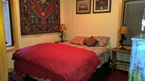 A bedroom with a bed, two bedside lamps, a window with blinds, and a wall with two framed pictures. - Lakeside cabin retreat; perfect getaway for winter sports, four seasons of fun (Hayward)