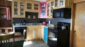 A kitchen with wooden cabinets, a microwave, a stove, and a sink. - Lakeside cabin retreat; perfect getaway for winter sports, four seasons of fun (Hayward)