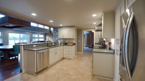 A spacious kitchen with a central island, stainless steel appliances, and a view to the backyard. - Private Executive Home with Pool, Pickleball Court, and Sauna. (Gearhart)