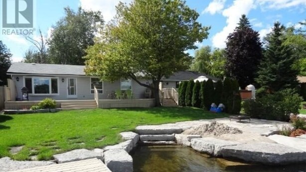 A residential property with a small pond, a wooden deck, and a well-maintained lawn.