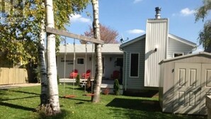 A residential property with a fenced backyard, a small shed, and a house with a porch.