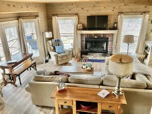 Un salon chaleureux avec une cheminée, des fauteuils confortables et un téléviseur.