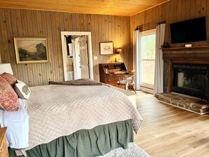 Une chambre confortable avec un grand lit, un bureau, une cheminée et un téléviseur.