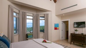 Une chambre d’hôtel avec un grand lit, une commode, une télévision et une vue sur l’extérieur.