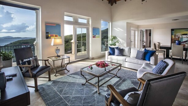 Un salon spacieux avec balcon, ventilateur de plafond et vue sur la mer.