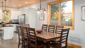 A modern kitchen with wooden cabinets, a central island, and a dining area with a wooden table and chairs.