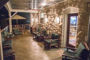 Un espace extĂ©rieur abritĂ©, dotĂ© de murs en pierre, de mobilier en bois et dâun tĂ©lĂ©viseur.