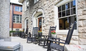 A stone building with a row of black rocking chairs and potted plants. - The Stone House at Black Dog Salvage (Roanoke)
