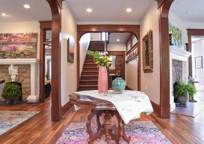Un couloir avec une table en bois, un escalier et une cheminée.