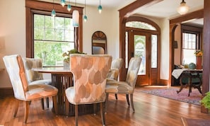 Un comedor con una mesa y sillas de madera, ventanas amplias y vistas al exterior.