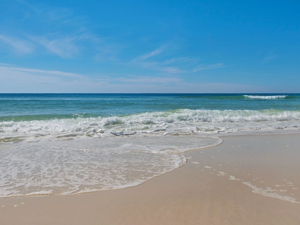 Enjoy a serene beach experience with calm ocean waves gently lapping onto the shore.
