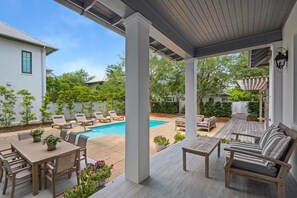 Relax by the pool surrounded by a deck, lounge chairs, and a sofa.