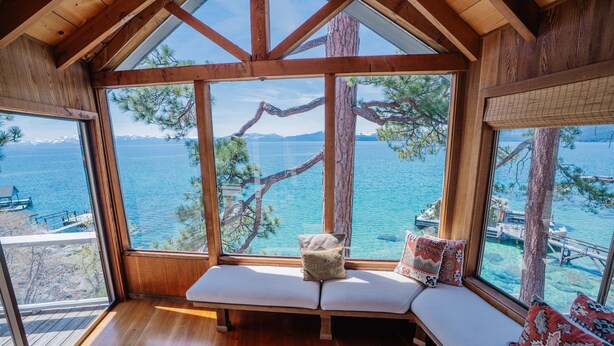 A wooden interior with a bench and large windows overlooking a body of water. - Peaceful Lakefront Home with Gorgeous Lakeviews and Hottub, Lake St. Lakefront by Tahoe Time VR (Kings Beach)