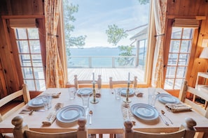 A wooden dining table set for six with a view of the sea.