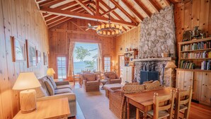 A wooden cabin interior with a stone fireplace, wicker furniture, and a bookshelf. - Peaceful Lakefront Home with Gorgeous Lakeviews and Hottub, Lake St. Lakefront by Tahoe Time VR (Kings Beach)