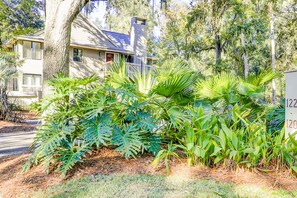 Situated in a wooded area, this traditional two-story house offers a serene environment surrounded by lush greenery and a prominent tree.