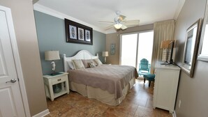 Ein Schlafzimmer mit einem Bett, Nachttischen, einem Deckenventilator und Blick ins Freie.
