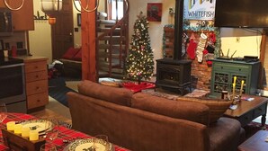 A cozy living room with a plaid table set for a meal, a fireplace, and a Christmas tree. - Whitefish Mountain Resort, Ski In Ski Out Condo, 3 Bed 2 Bath, Private Hot Tub! (Whitefish)