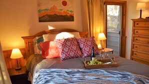 A neatly made bed with a blue blanket, two bedside lamps, a wooden dresser, and a painting on the wall. - Whitefish Mountain Resort, Ski In Ski Out Condo, 3 Bed 2 Bath, Private Hot Tub! (Whitefish)