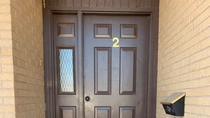 A brown double door with the number 2, a small window, and a mailbox on the right side.