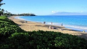 A beach with people, clear skies, and a mountain in the background. - A403 - Spacious 1 Bedroom, 2 King Bed, Garden and Partial Ocean Views (Lahaina)