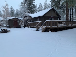 A cabin with a wooden deck and a covered picnic table.
