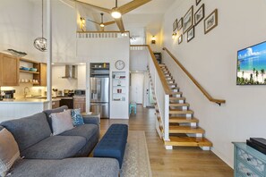 A spacious living area with a sofa, a staircase, a kitchen, and a dining area.
