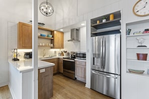 Kitchen with a full-size refrigerator, range, microwave, and counter space.