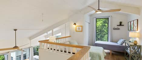 A spacious loft bedroom with a large window, a balcony, and a ceiling fan.